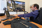 Michal Martinka testuje tričko proti únavě s pomocí hry Euro Truck Simulator 2. Výzkumníkovi, který má k dispozici ovládací panel, řadí i šlape na pedály, umožňuje napodobit jíjzdu v kamionu. Foto: Adam Pluhař